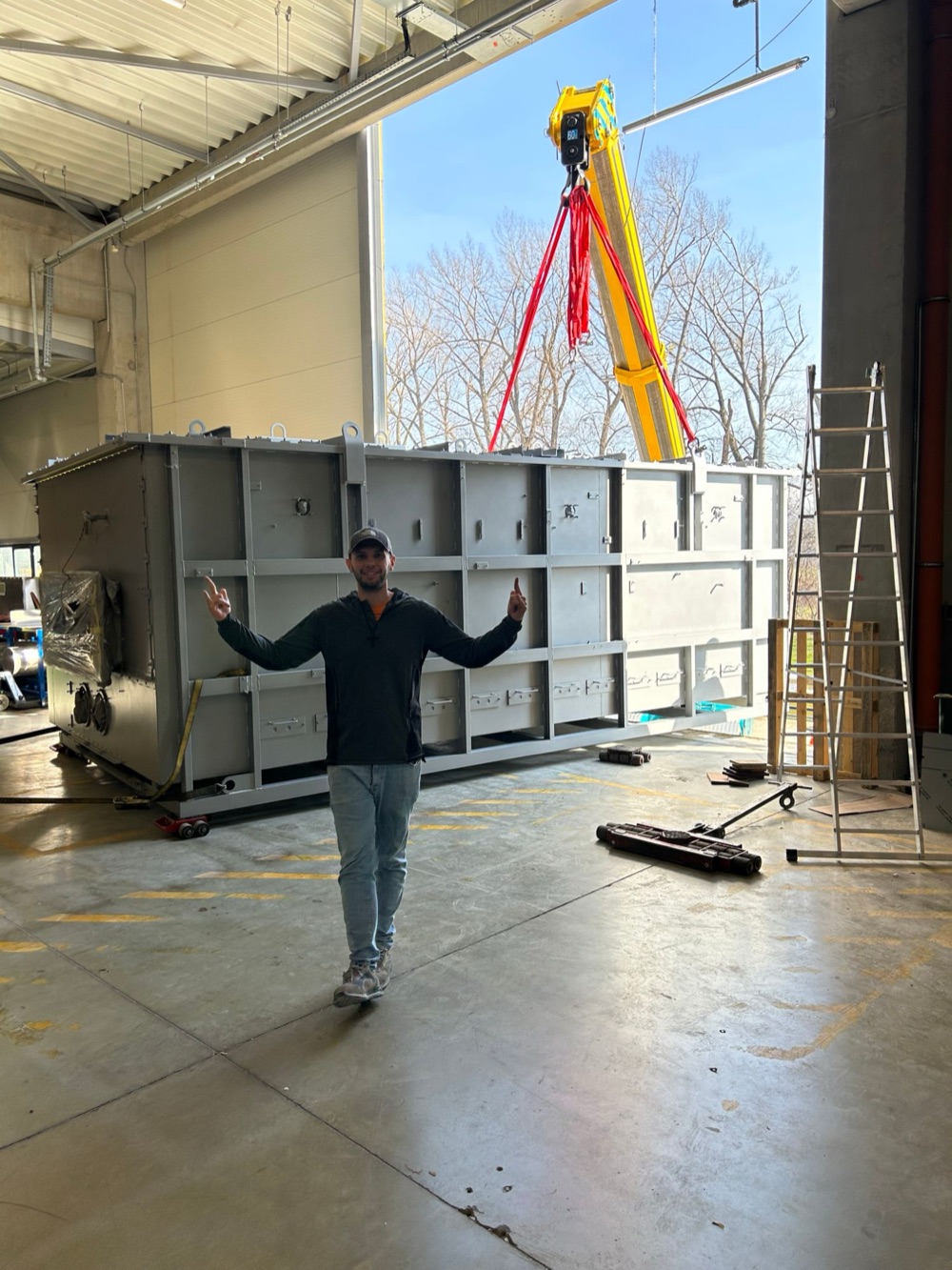 Ľubomír Blažek in a production hall in front of a large steel housing being lifted by a crane